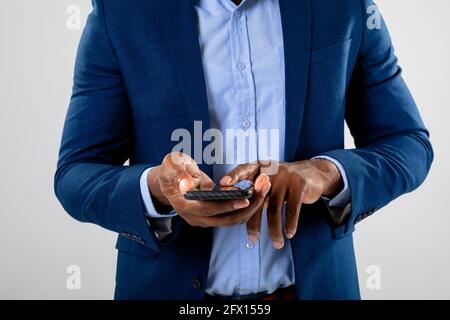 Mid section of businessman using fingerprint scanner on smartphone against grey background Stock Photo