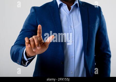 Mid section of businessman touching invisible screen against grey background Stock Photo