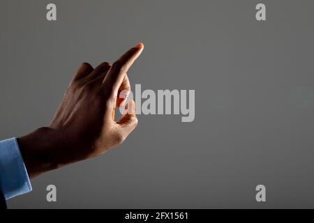Close up of businessman touching invisible screen against grey background Stock Photo