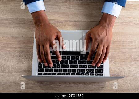 Over head view of businessman using laptop on wooden table Stock Photo