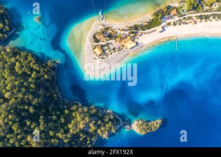 Aerial view of sandy beach green trees, mountain at sunset