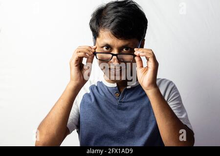 A middle aged Indian man smiling and looking over eyeglasses on white background Stock Photo