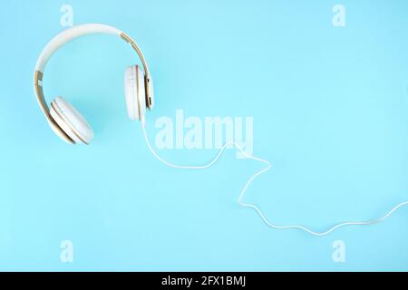 White headphones on blue background with copy space. Flat lay. Music concept Stock Photo