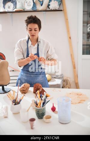 Potter sitting at the table and preparing for handbuilding clay Stock Photo