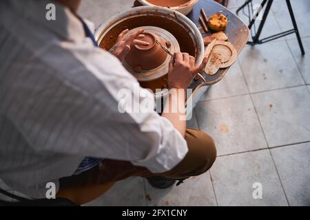 Craftsman smoothing bottom of bowl with tool and finger Stock Photo