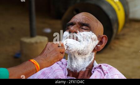 01 January 2021- Reengus, Sikar, India. Indian rural shot, traditional barber shaving old man in village of rajasthan, India. Stock Photo