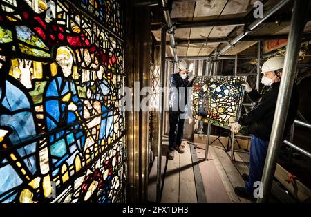 Conservator Matthew Nickels (left) and Master Glazier Tony Cattle (right) from York Glaziers Trust removed a stained glass window panel at the start of a new five year, £5m project to conserve York Minster's South East Transept and its medieval St Cuthbert Window. Picture date: Tuesday May 25, 2021. Work is being undertaken by York Glaziers Trust to remove stained glass panels from the window, which is nearly 600-years-old and one of the largest surviving narrative windows in the world. The project involves major conservation and restoration works to both the stained glass and stone elements o Stock Photo