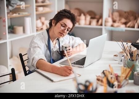 Smart pottery shop owner writing in notebook Stock Photo