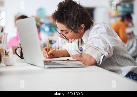 Female with short haircut concentrated on writing in notepad Stock Photo
