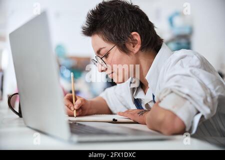 Pottery shop employee designing new product in notebook Stock Photo