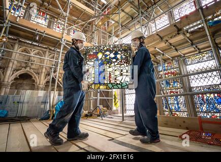 York Glaziers Trust employees Kieran Muir (left) and Emily Price (right) remove a stained glass window panel at the start of a new five year, £5m project to conserve York Minster's South East Transept and its medieval St Cuthbert Window. Picture date: Tuesday May 25, 2021. Work is being undertaken by York Glaziers Trust to remove stained glass panels from the window, which is nearly 600-years-old and one of the largest surviving narrative windows in the world. The project involves major conservation and restoration works to both the stained glass and stone elements of the window and the South  Stock Photo