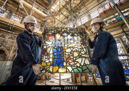 York Glaziers Trust employees Kieran Muir (left) and Emily Price (right) remove a stained glass window panel at the start of a new five year, £5m project to conserve York Minster's South East Transept and its medieval St Cuthbert Window. Picture date: Tuesday May 25, 2021. Work is being undertaken by York Glaziers Trust to remove stained glass panels from the window, which is nearly 600-years-old and one of the largest surviving narrative windows in the world. The project involves major conservation and restoration works to both the stained glass and stone elements of the window and the South  Stock Photo