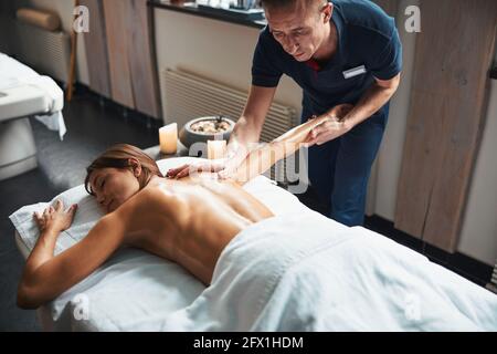 Beautiful caucasian woman under the towel relaxing while getting manual massage in spa salon Stock Photo