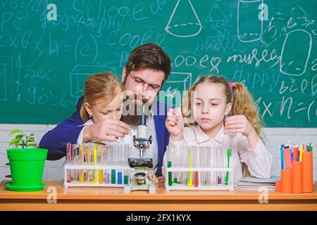 Explaining biology to children. How to interest children study. Fascinating biology lesson. Man bearded teacher work with microscope and test tubes in Stock Photo