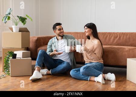 Happy man and woman drinking coffee sitting on floor Stock Photo