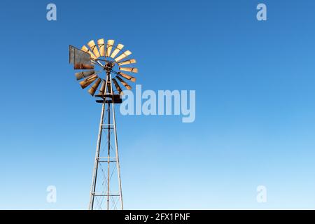 Old rusty wind turbine against a blue sky background Stock Photo