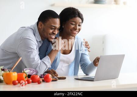 Happy black pregnant couple looking for recipes online Stock Photo