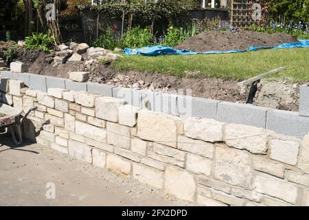 A stone faced garden retaining wall under construction Stock Photo