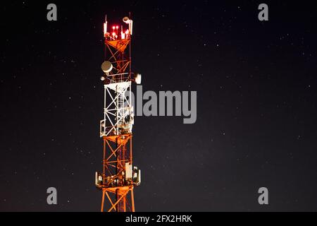 Against the background of the starry sky, the mobile communication towers of the 4g and 5g systems. Cellular base station at night Stock Photo