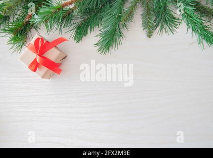 Decorated fir branch on tree with Gift box on wood background. Space for text Stock Photo