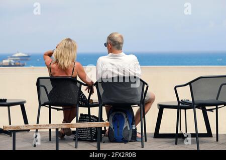 Monte-Carlo, Monaco - June 16, 2019: Rear View Of A Couple Of Tourists Sitting At A Bar And Looking At The Mediterranean Sea In Monte-Carlo, Monaco On Stock Photo