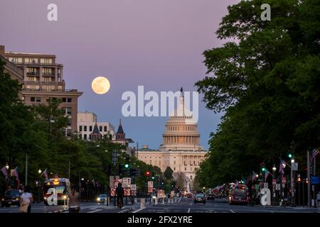 The last rays of the sun set on the United States Capitol Building as the moon rises over Washington, D.C. Stock Photo