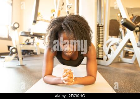 Young woman doing plank to exercising core body in fitness gym.