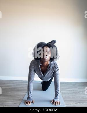 Young woman doing yoga exercise on yoga mat in home studio, one person, close up, natural hair, black woman, african american Stock Photo