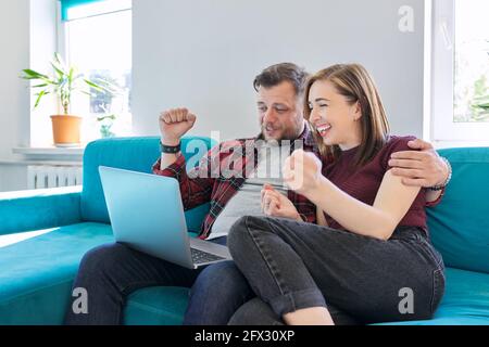 Luck, happiness, joy, victory, won, happy emotional middle aged couple looking in laptop Stock Photo