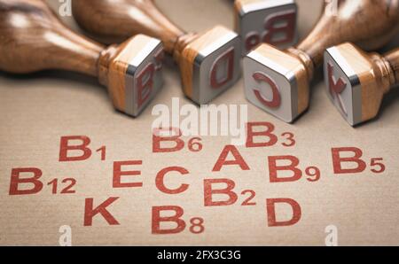 3D illustration of many rubber stamps and complete list of 13 essential vitamins printed on kraft paper. Stock Photo