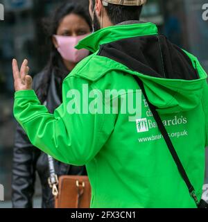 Believe in Children, green uniformed Charity Barnandos fundraisers. Paid street fundraisers are known as chuggers or charity muggers collecting cash, donations, subscriptions in Preston city centre, UK Stock Photo