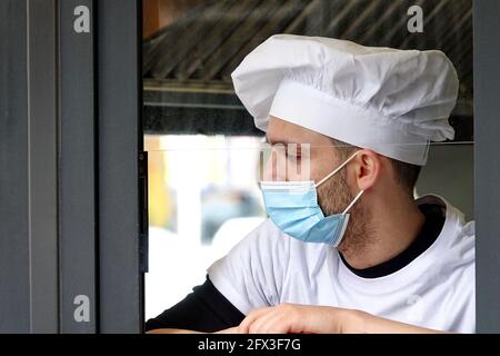 A young chef wearing a covid mask during a work break. Milan, Italy - May 2021