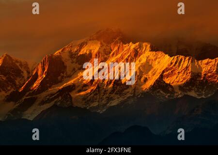 Orange sunset on Chaukhamba peaks, a mountain massif in the Gangotri Group of the Garhwal Himalaya. It lies at the head of the Gangotri Glacier at Utt Stock Photo