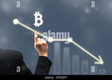 Businessman pointing digital bitcoin icon. Chart and diagram, graph of falling bitcoin prices. Virtual cryptocurrency stock exchange concept Stock Photo