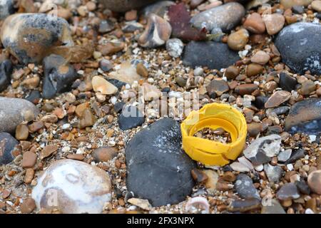 A yellow plastic bottle top on the beach Stock Photo