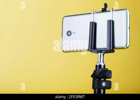 Smartphone on a tripod on a yellow background for blogging. Concept Stock Photo