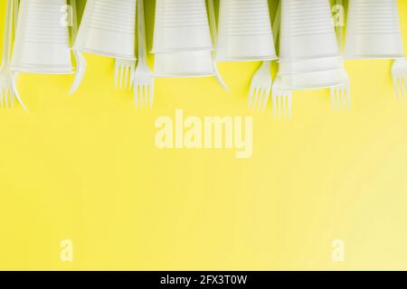 Plastic tableware on a yellow background with free space. Disposable tableware Stock Photo