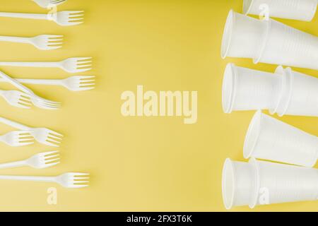 Plastic tableware on a yellow background with free space. Disposable tableware Stock Photo