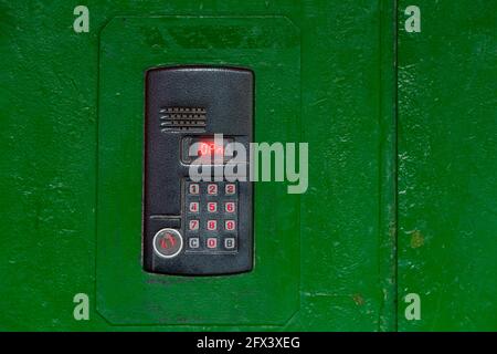 An intercom on green painted red steel surface with a keypad, digital display and rfid sensor for calling close-up. Stock Photo