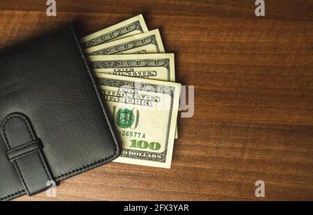 Money in black leather wallet on wooden table, finance and business concept, top view Stock Photo