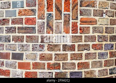 Old masonry of multicolored bricks in different shades of red and black Stock Photo