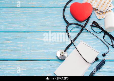 A heart with a stethoscope lies on a light wooden background. Healthy heart. Stock Photo