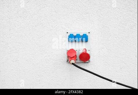 Industrial high voltage sockets mounted on a white wall. Stock Photo
