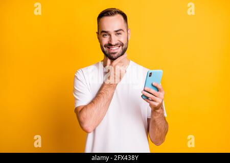Portrait of nice cheerful guy holding in hand using gadget browsing 5g smm isolated over bright yellow color background Stock Photo