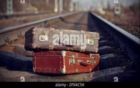 The image of two old vintage suitcases on railway tracks. Stock Photo
