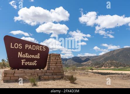 Los Padres National Forest, CA, USA - May 21, 2021: Beige on brown sign at eastern entrance of the park under blue cloudscape and mountains on horizon Stock Photo