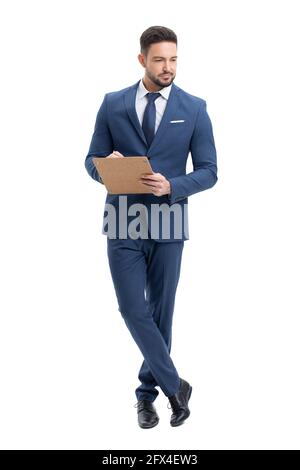 Young professional businessman holding clipboard while relaxing, isolated on white background Stock Photo