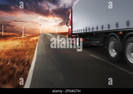 Red modern truck moving fast on the road at sunset Stock Photo