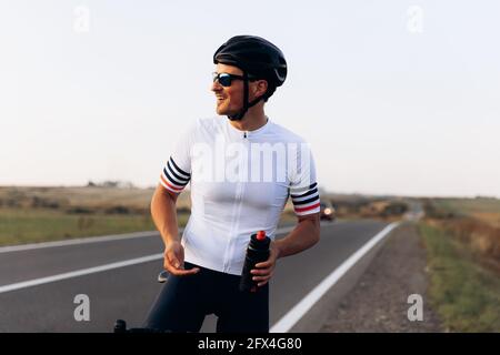 Smiling man in cycling clothing standing outdoors Stock Photo