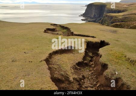 A large crack in the ground above the sea cliffs on the west coast of the Isle of Skye, Scotland, British Isles. Stock Photo